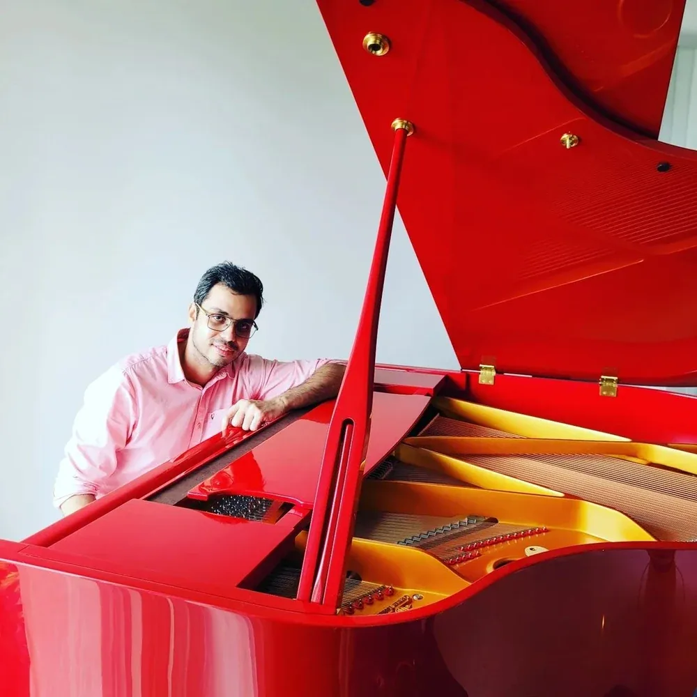 Mark Parakh beside a red grand piano